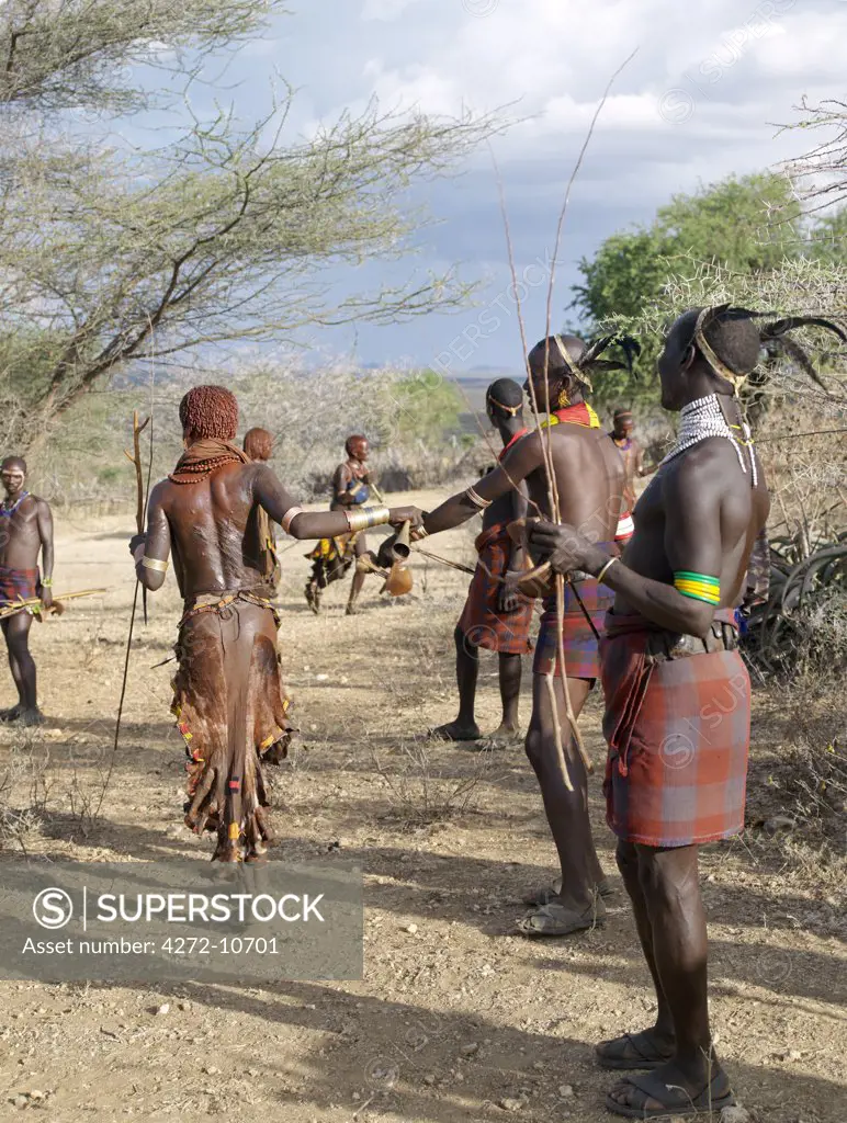 A Hamar woman implores a man to whip her at a Jumping of the Bull ceremony. Female friends and relatives of the initiate are willing whipped with pliable sticks to show their solidarity and love for him. The Hamar are semi nomadic pastoralists of Southwest Ethiopia whose women wear striking traditional dress and style their red ochred hair mop fashion.