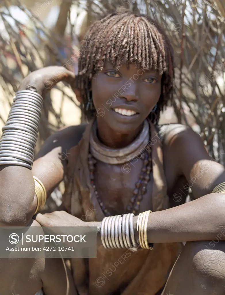 A Hamar woman at Turmi Market.The Hamar are semi-nomadic pastoralists of Southwest Ethiopia whose women wear striking traditional dress and style their red-ochred hair mop-fashion.   Skins are widely used for clothing and heavy metal necklaces, bracelets and anklets form part of their adornments.