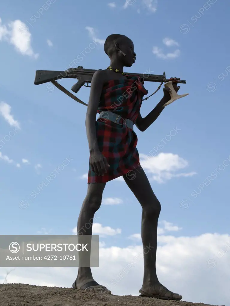 Silhouette of an armed Nyagatom herdsman on the banks of the Omo River.  Almost every male member of the tribe owns a rifle, the majority of which are AK47 assault rifles. The Nyagatom are one of the largest tribes and arguably the most warlike people living along the Omo River in Southwest Ethiopia.