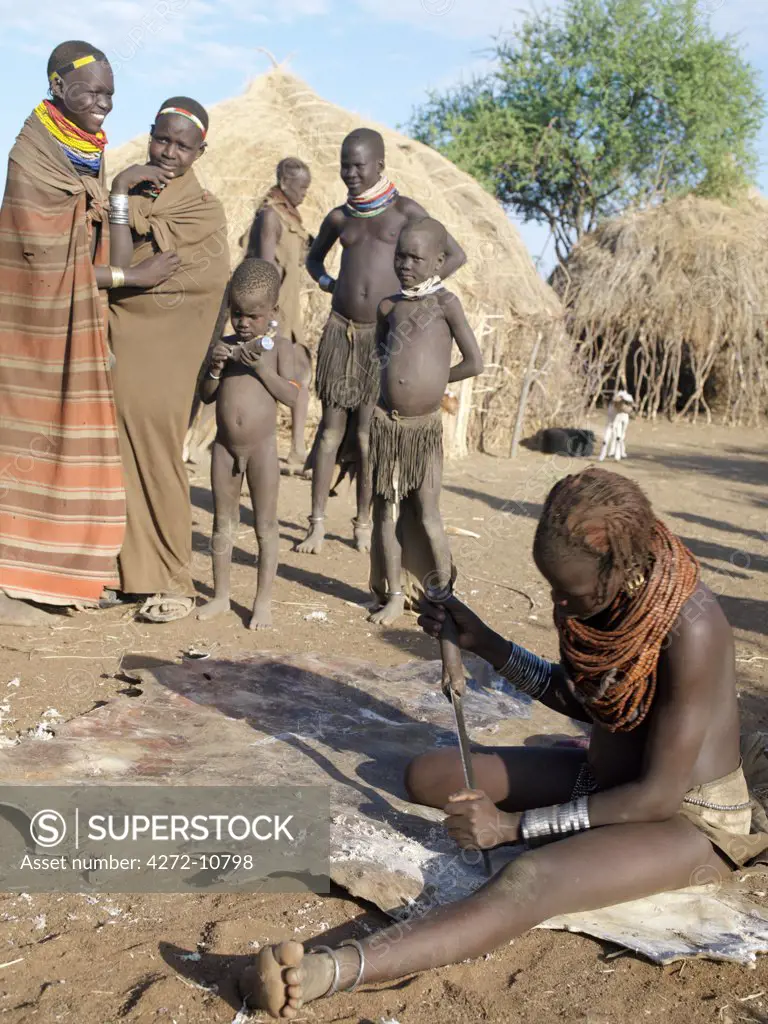 While friends look on, a Nyagatom woman scrapes the back of a cowhide to remove the dried flesh and blood. The Nyagatom are one of the largest tribes and arguably the most warlike people living along the Omo River in Southwest Ethiopia.