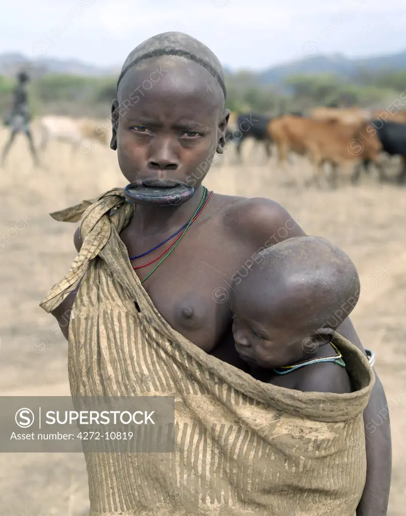A Mursi mother and child.  The mother is wearing a large clay lip plate.  Shortly before marriage, a girls lower lip will be pierced and progressively stretched over a year or so while some of her teeth will be removed for the plate to fit snugly. The size of the lip plate often determines the quantum of the bride price.   The reason for this singular practice is not fully understood but Mursi women claim that it enhances their beauty.