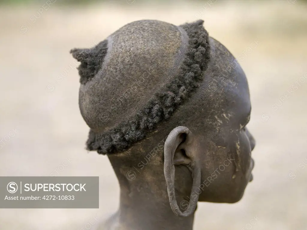 The typical hairstyle of a young Mursi girl. The Mursi speak a Nilotic language and have affinities with the Shilluk and Anuak of eastern Sudan.  They live in a remote area of southwest Ethiopia along the Omo River.