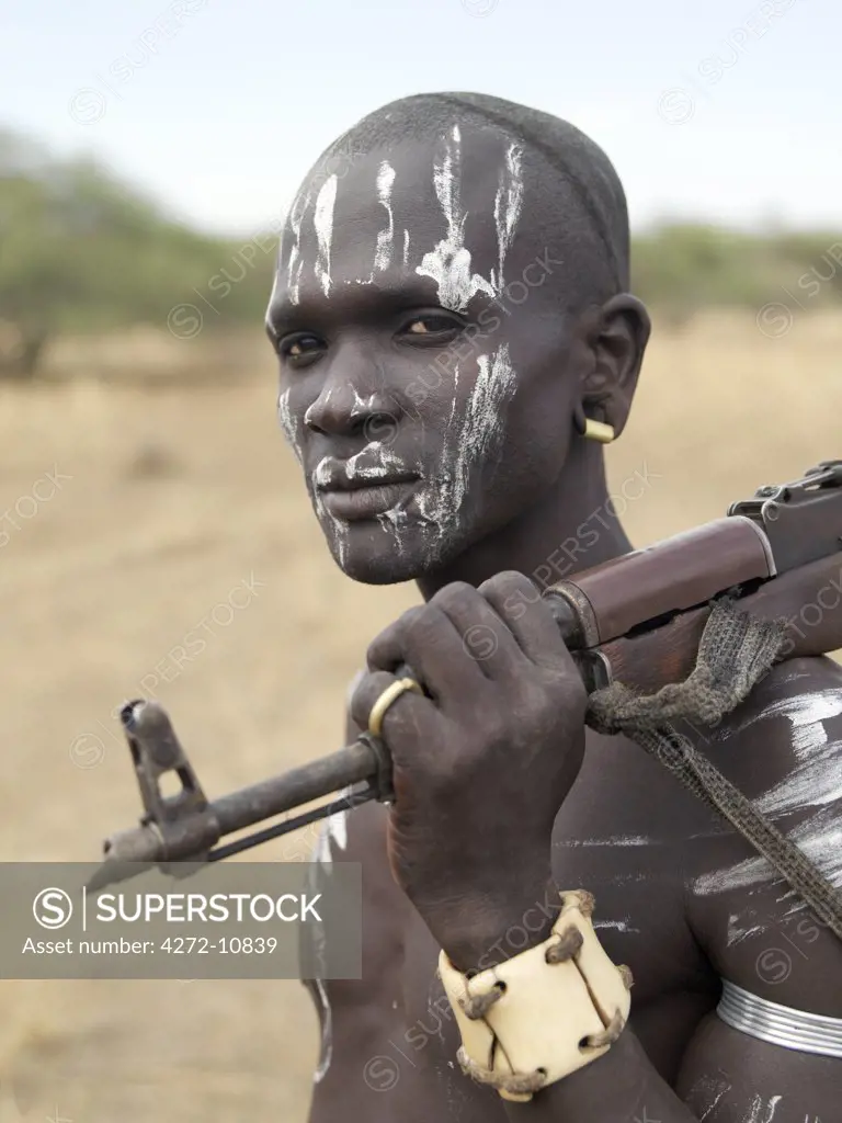 An armed Mursi man wearing a heavy ivory bracelet round his left wrist.The Mursi speak a Nilotic language and have affinities with the Shilluk and Anuak of eastern Sudan.  They live in a remote area of southwest Ethiopia along the Omo River.