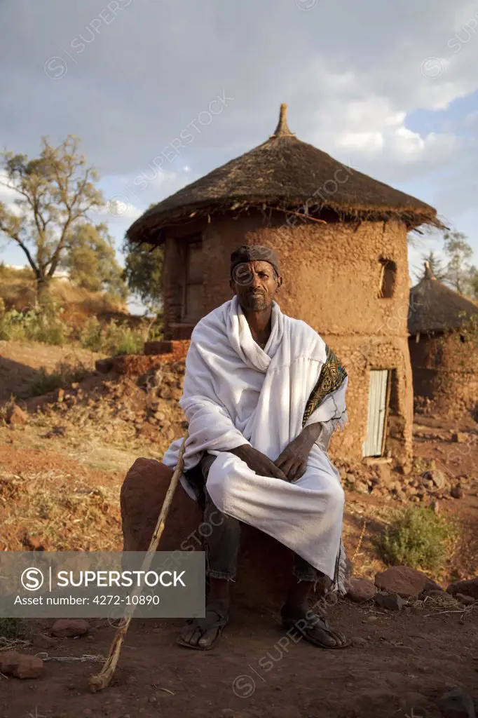Ethiopia, Lalibela. A Christian man sits in front of his house in Lalibela at sunset.