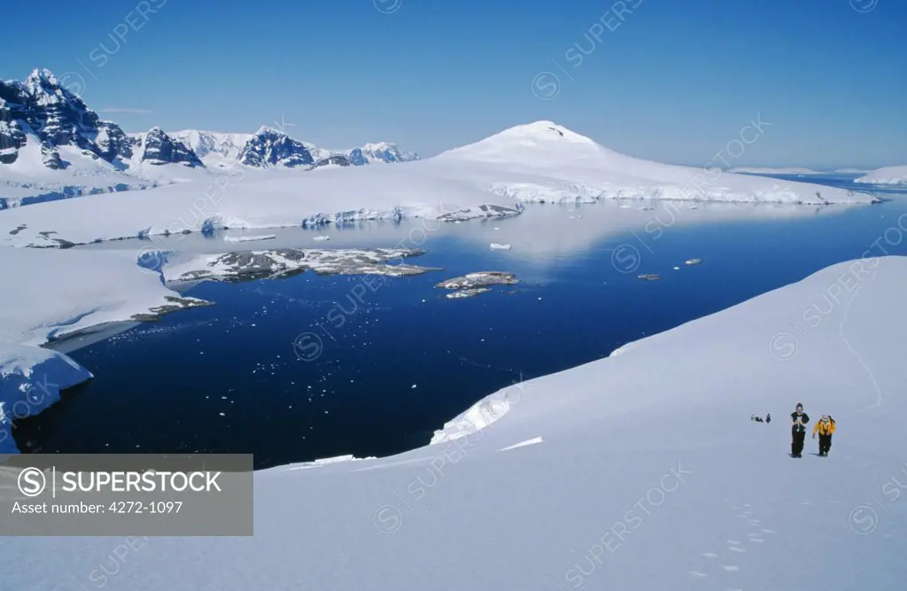 Antarctica, Wiencke Island, Port Lockroy. Cruise ship tourists walking on a snow field above Port Lockroy.