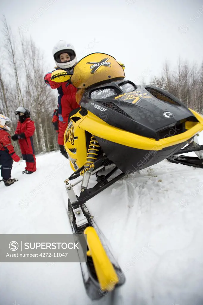 Finland, Pielinen region of North Koralia in Finnish Lapland. Girl on snowmobile (or skidoo) safari. (MR)