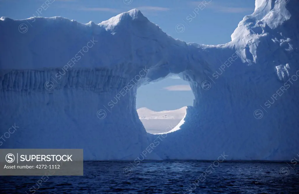 Antarctica, Grandidier Channel. Weathered iceberg with a circular window near Booth Island.