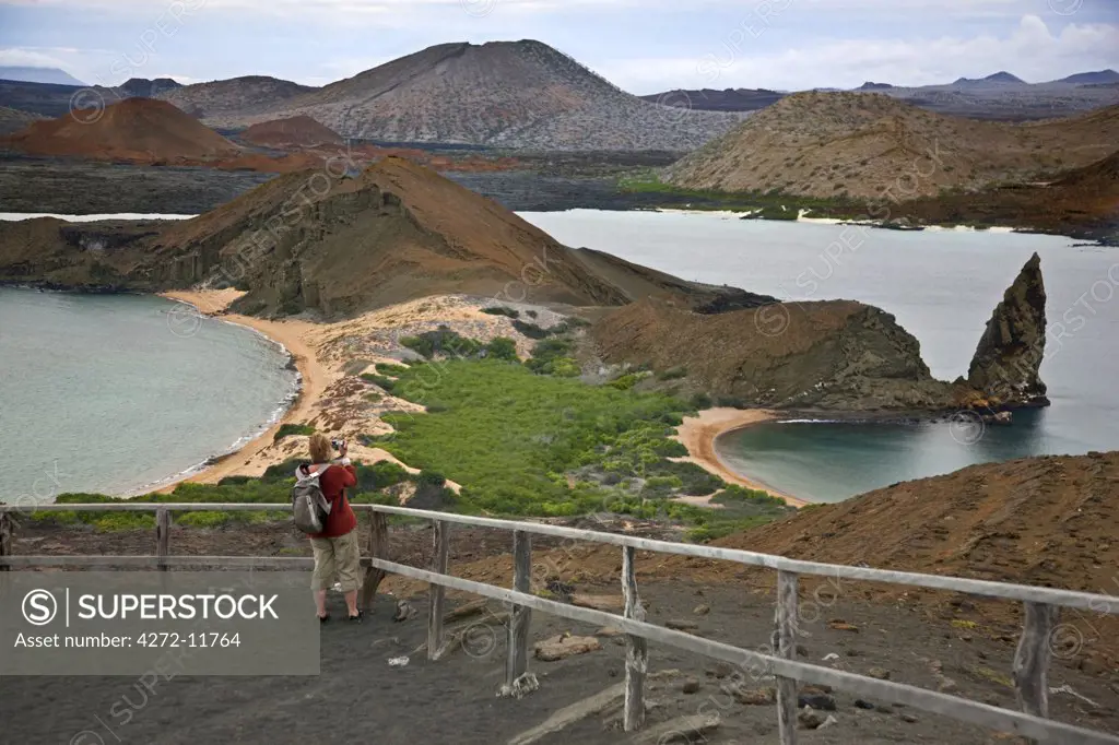Galapagos Islands, A visitor photographs the view from the top of Bartolome Island looking across to Santiago Island.  The volcanic origins of these islands is self-evident.