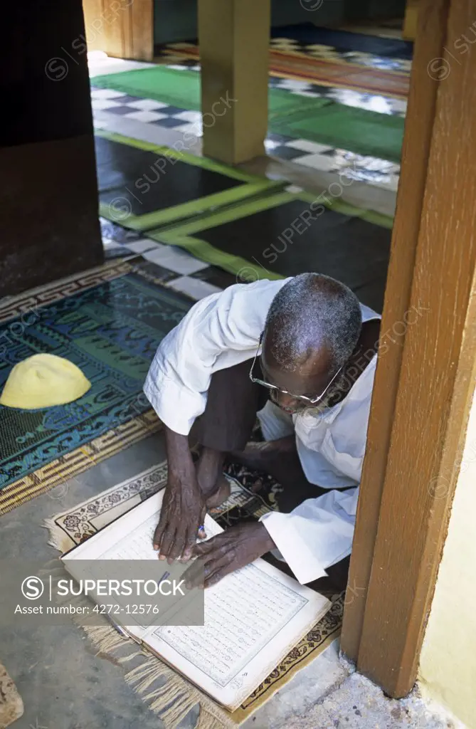 Ghana, Northern region, Tamale. A Muslim prays and reads the Quran at a Mosque in Tamale during Ramadan.