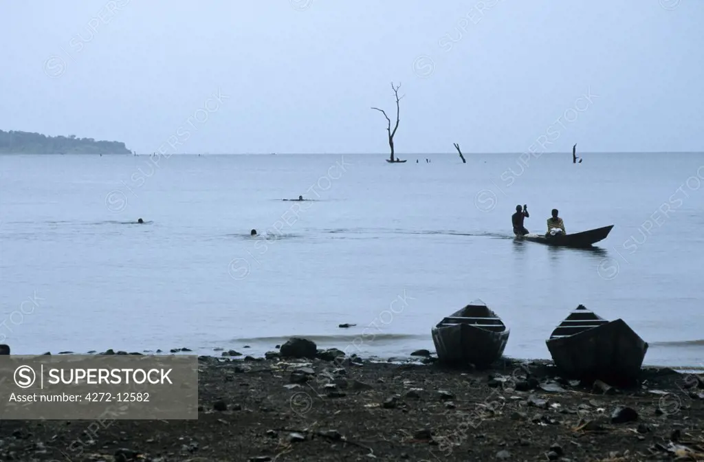 Ghana, Volta Region, Lake Volta. Canoes and swimmers on Lake Volta's shores. The largest man made lake in the world.