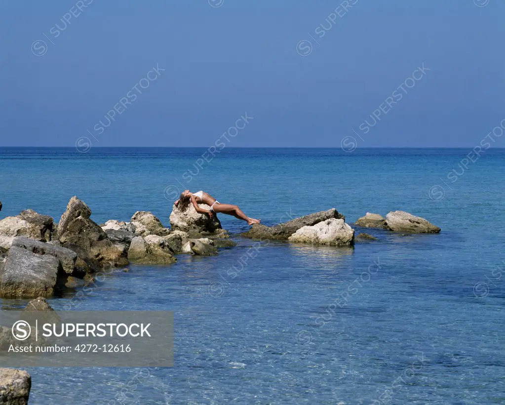 Girl sunbathing on rocks on Boussolos Beach