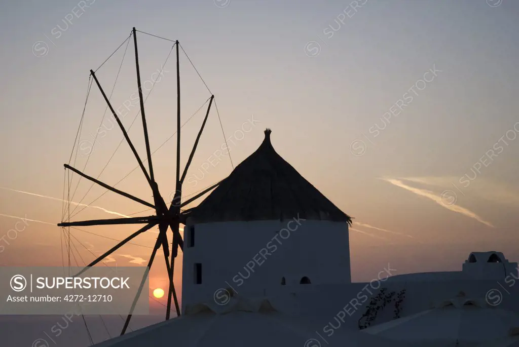 Sunset behind a windmill in the town of Oia, Santorini, Greece