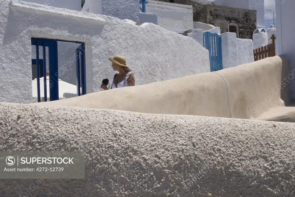 Greece, Santorini, Pyrgos. Tourist exploring the narrow streets in the whitewashed hill top village of Pyrgos.
