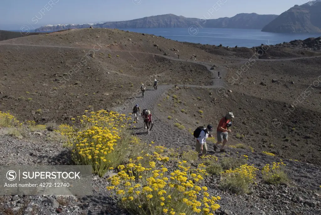 Greece, Santorini, Nea Kameni. Tourists treking on Nea Kameni, a small uninhabited volcanic island located in the Bay of Santorini.