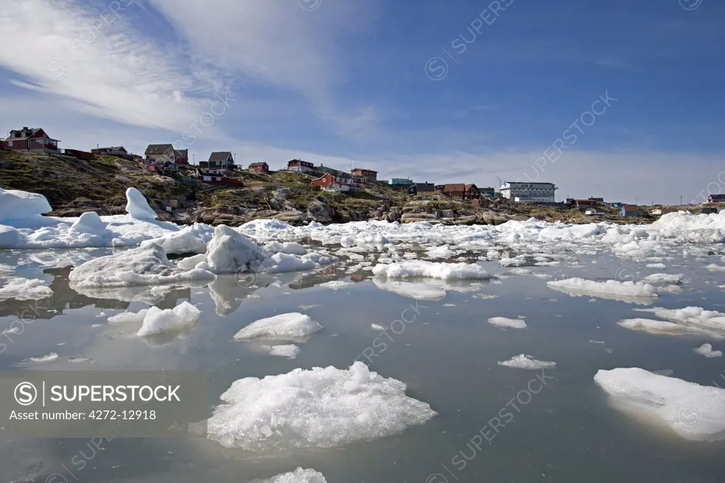 Greenland, Ilulissat, UNESCO World Heritage Site Icefjord.   Looking across the fjord full of bergy bits and growlers towards the shoreline and the modern but traditional style development along the coastline.