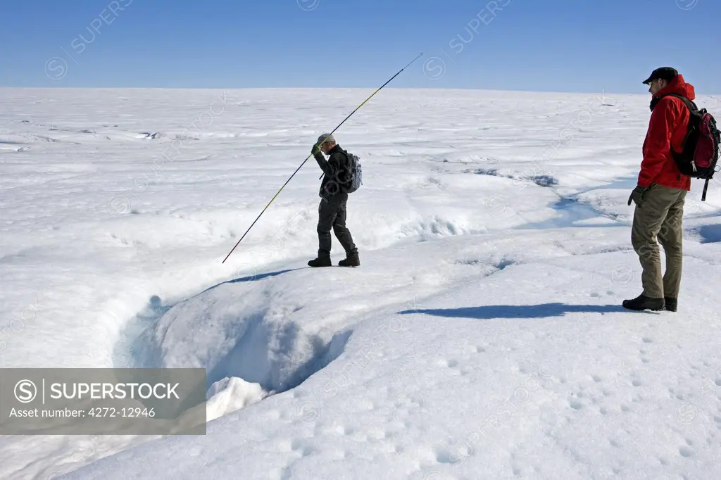 Greenland, Eqi Glacier, Greenland, Ice cap.   Walking up on the Greenland Icecap and testing the safety of the ice looking for unstable ice and crevasses with a snow probe.