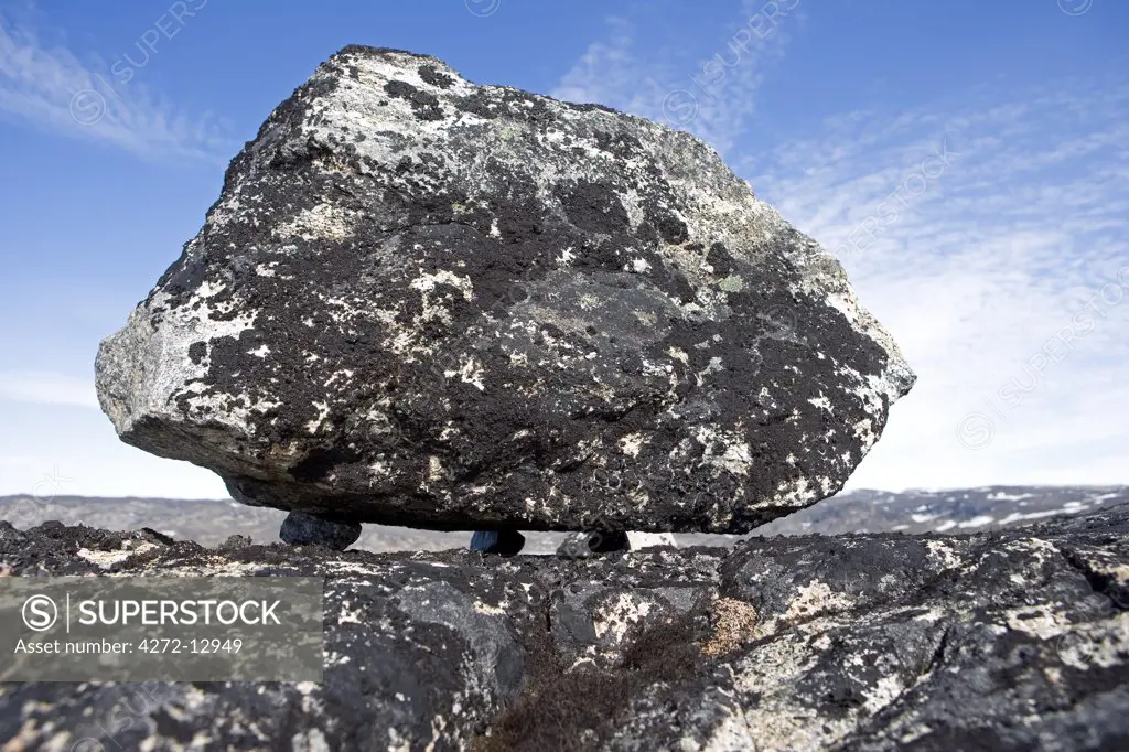 Greenland, Eqi Glacier.   The heavily glaciated landscape to the front of the Greenland Icecap, only recently free of ice, has left some fanstatic features such as this boulder left suspended on three small stones.