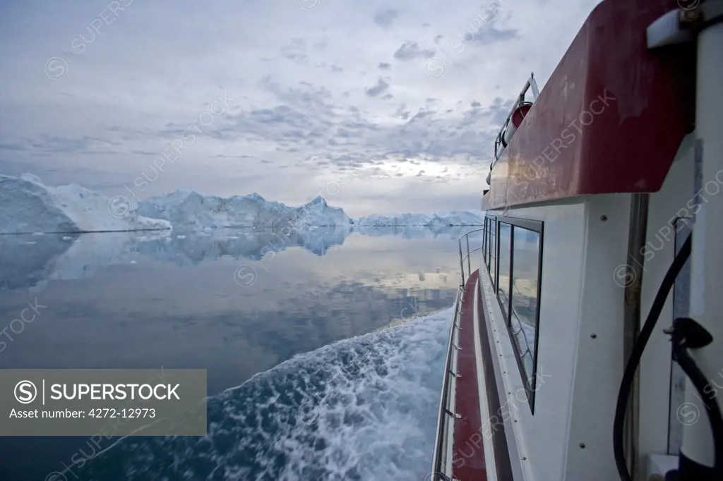 Greenland, Ilulissat, UNESCO World Heritage Site Icefjord. Sailing thorugh the Icefjord at midnight with the sky still light and with massive icebergs scattering the area.