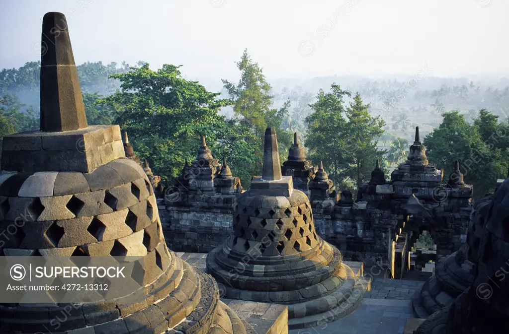 Latticed stupas on upper terraces, Borobodur temple, Java, Indonesia. Ranking with Pagan and Angkor as one of the greatest Southeast Asian monuments, Borobodor is an enormous construction standing majestically on a hill overlooking lush green fields and distant hills, 42km northwest of Yogyakarta.