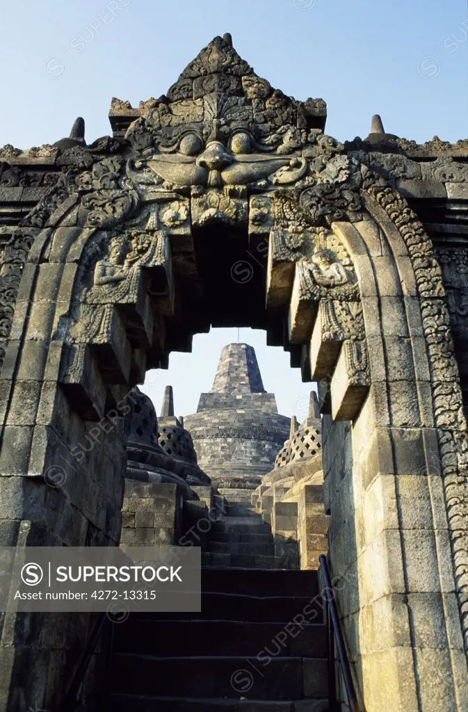 View to Grand Stupa from lower terrace through sculpted archway, Borobodur temple, Java, Indonesia. Ranking with Pagan and Angkor as one of the greatest Southeast Asian monuments, Borobodor is an enormous construction standing majestically on a hill overlooking lush green fields and distant hills, 42km northwest of Yogyakarta.