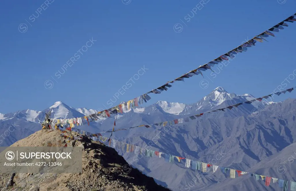Stok Mountains and prayer flags viewed from Leh.  Stok Kangri trekking peak prominent on right