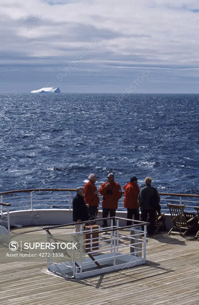 Antarctica, Antarctic Peninsula, Paradise Harbour. Passengers viewing giant tabular iceberg from stern of MV Discovery at the Chilean base in Paradise Harbour on the Antarctic Peninsula.