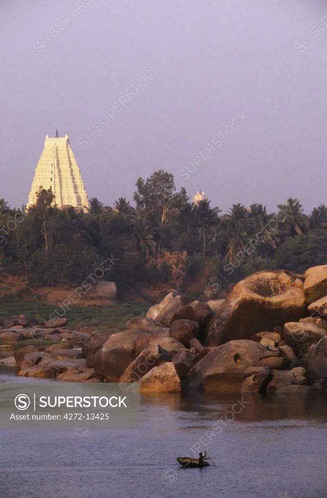 Fisherman's coracle on the Tungabhadra River with the great Virupaksha temple rising in the background