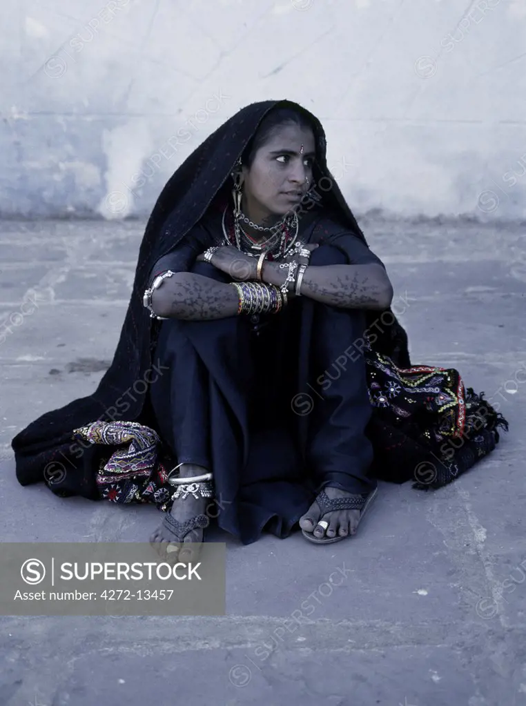 A Rabari woman sits at Than Monastery.  Rabari women usually wear black skirts and blouses edged with elaborate embroidery, as well as plentiful jewellery and tattoos.
