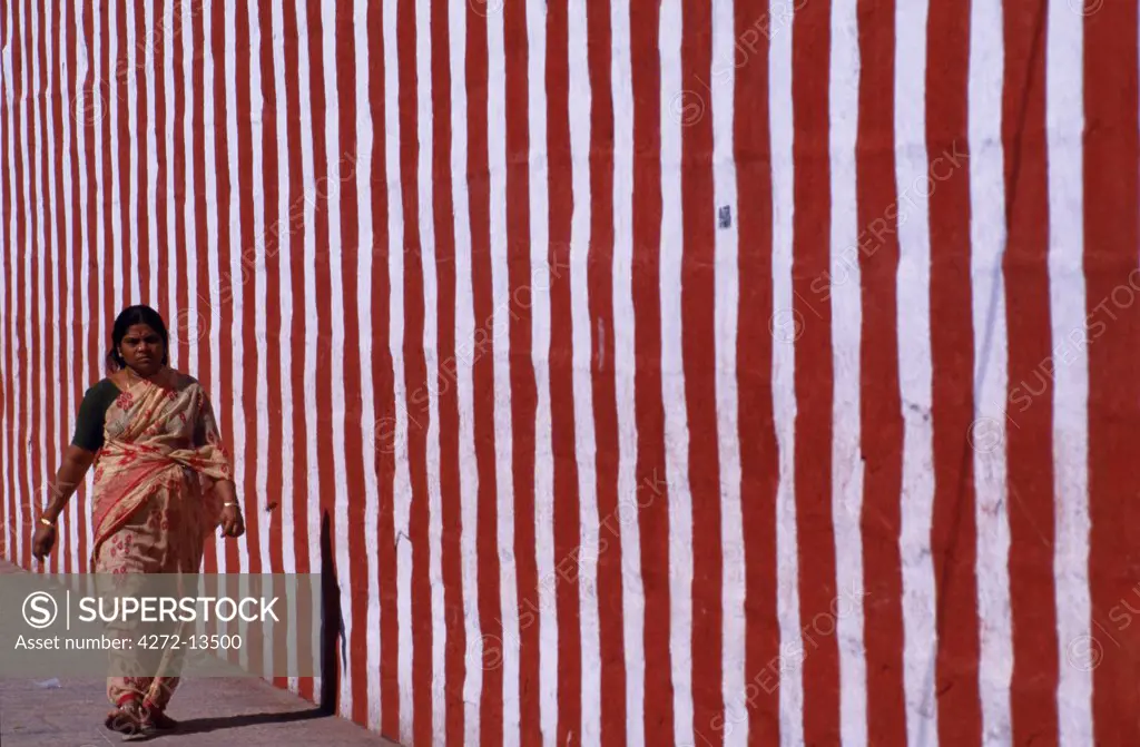 A pilgrim strolls by one of the Shri Meenakshi-Sundareshwarar temple's courtyard walls. It is one of India's largest temple complexes.