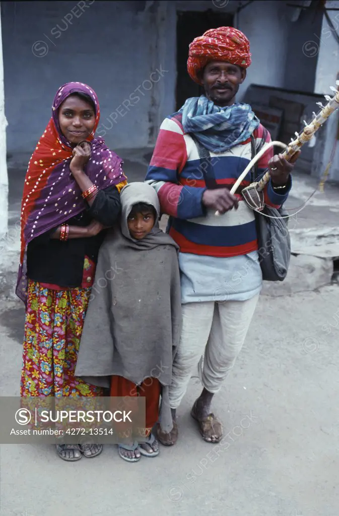 An itinerant musician - and his young family - in Pushkar street where they can earn a living busking for the pilgrims that throng this holy town.