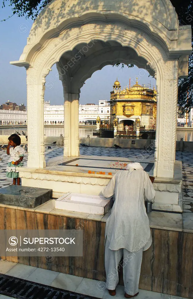 A pilgrim prays before a small shrine at the Sikh Golden Temple.