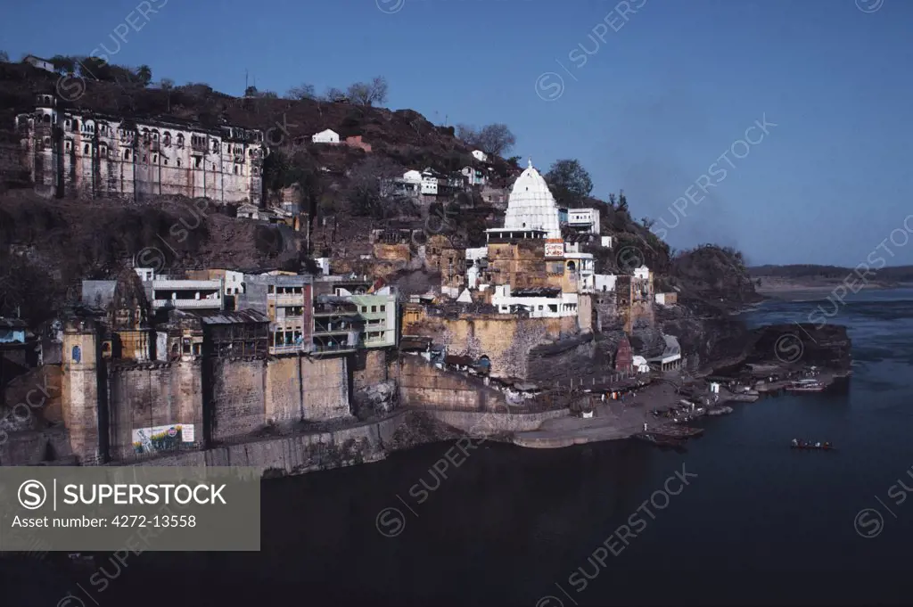 India, Madhya Pradesh, Omkareshwar. Situated on an island in the holy Narmada River, Omkareshwar is among the holiest spots in Central India. Here the dazzling white spire of the Shri Omkar Mandhata temple rises above a clutter of shops and stalls selling religious paraphernalia.