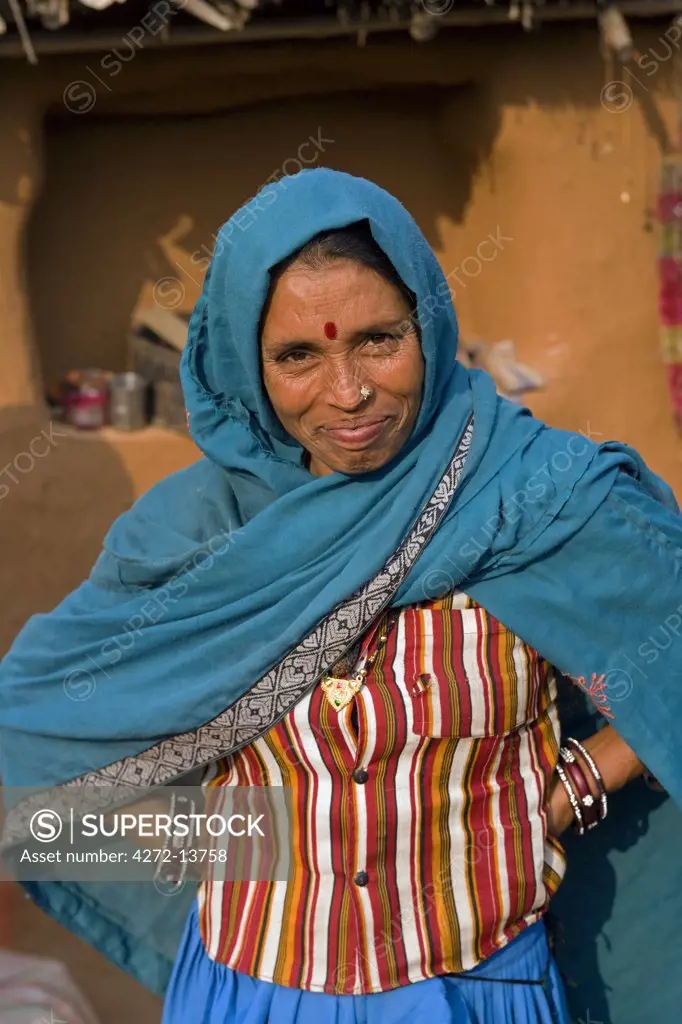 India, Rajasthan, Jaipur, Sariska.  The matriarch of a small farming household takes a break from preparing lunch to pose for the camera.