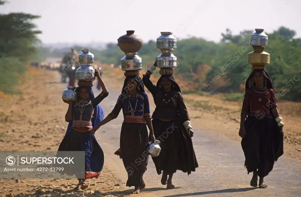 Harigin tribal woman carrying water jugs near the village of Nagpur.