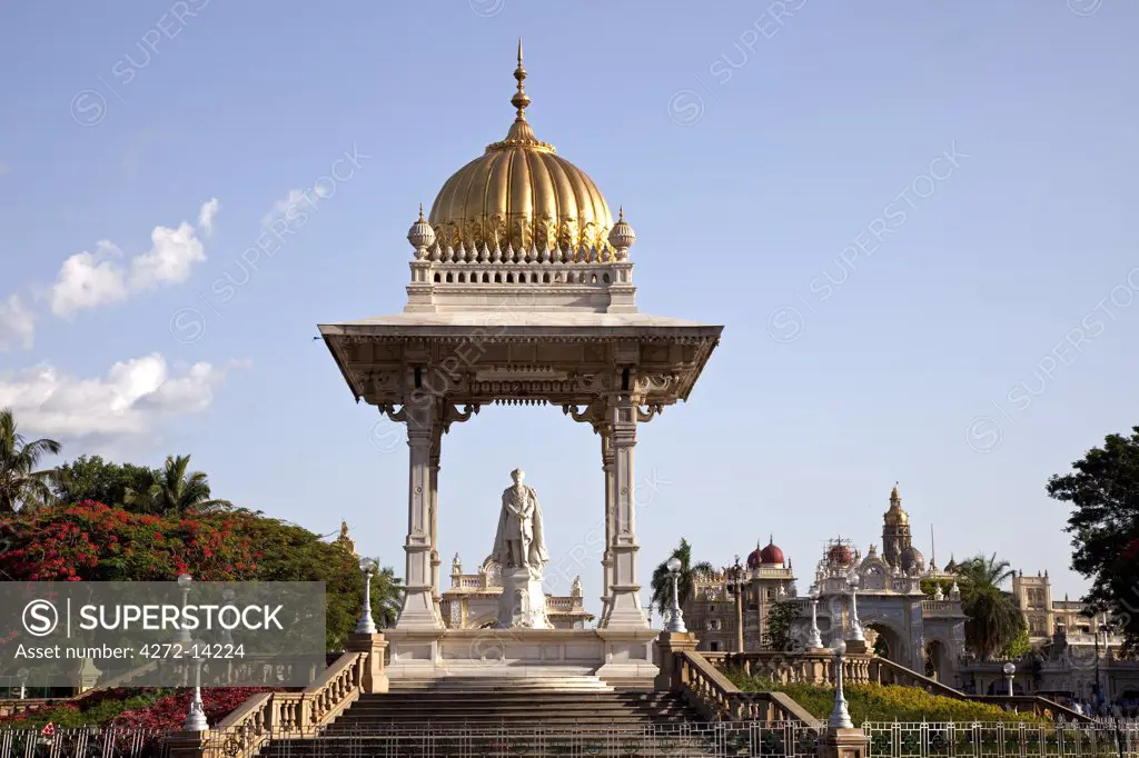 India, Mysore. A statue of the Maharaja Krishnaraja Wodeyar in the centre of a roundabout in Mysore, with Mysore Palace in the background.