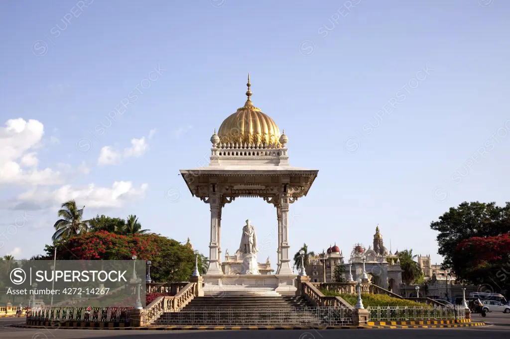India, Mysore. A statue of the Maharaja Krishnaraja Wodeyar in the centre of a roundabout in Mysore, with Mysore Palace in the background.