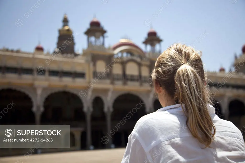 India, Mysore. A tourist looks at the front of Mysore Palace. MR