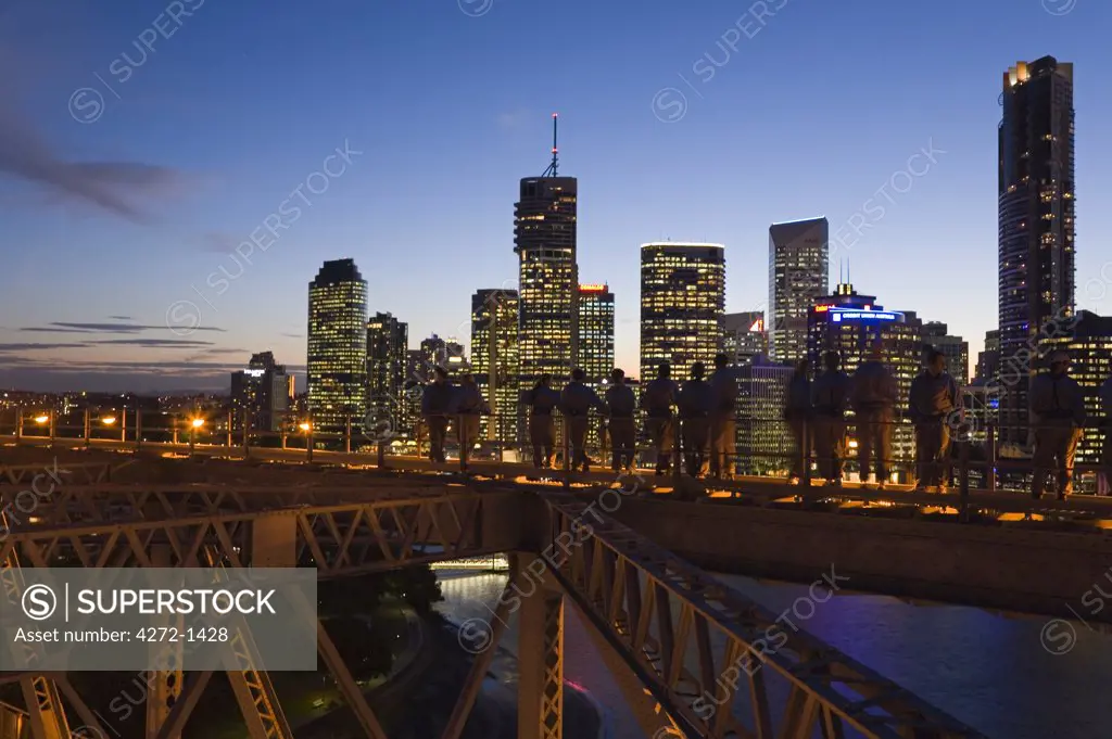 Australia, Queensland, Brisbane. A group of climbers on Brisbane's Story Bridge are silhouetted against the illuminated city skyline.  The Story Bridge Adventure Climb opened in 2005 and is one of only four such experiences in the world.
