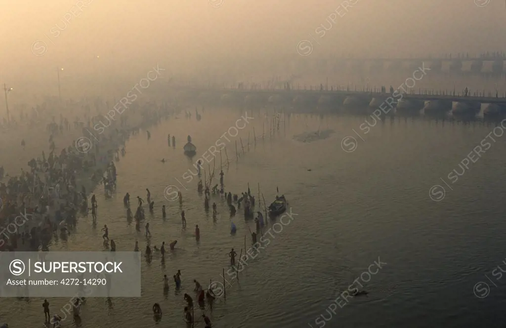 India, Uttar Pradesh, Allahabad. Hindu pilgrims bathe beside temporary pontoon bridges across the River Ganges built to help ease the vast numbers of pilgrims attending the celebrated Kumbh Mela festival held here every twelve years.