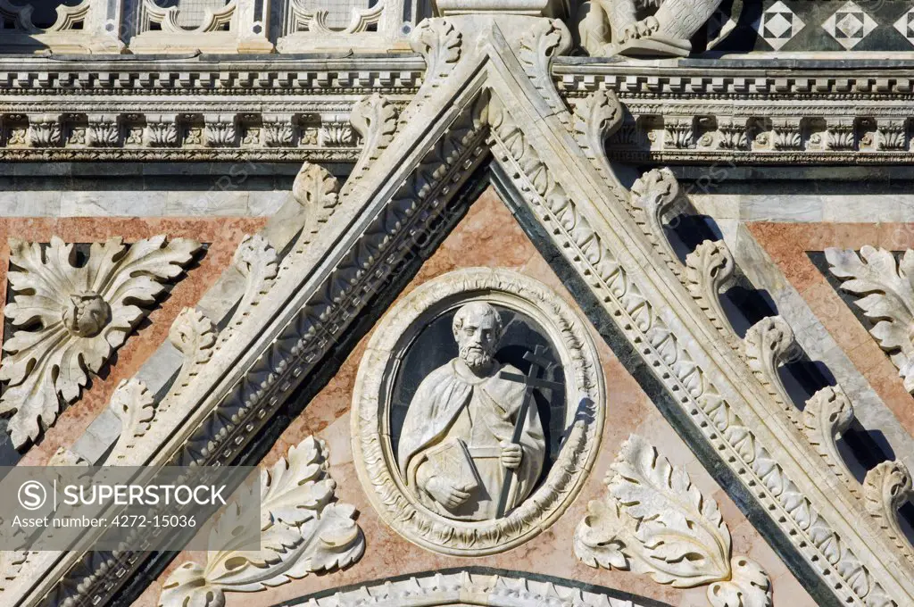 Italy, Tuscany, Siena. Detail of the elaborate carving and marble statues on the facade of the Duomo, Siena's Gothic cathedral.