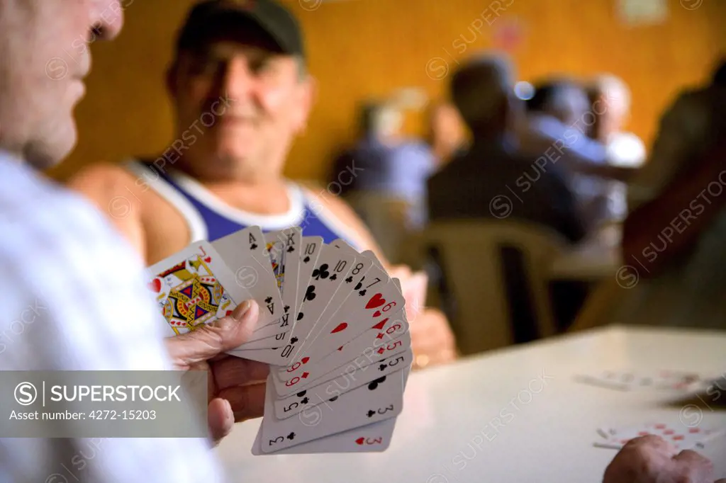 Southern Italy, Sicily, Pozzallo. Retired men killing time by playing cards in a typical club.