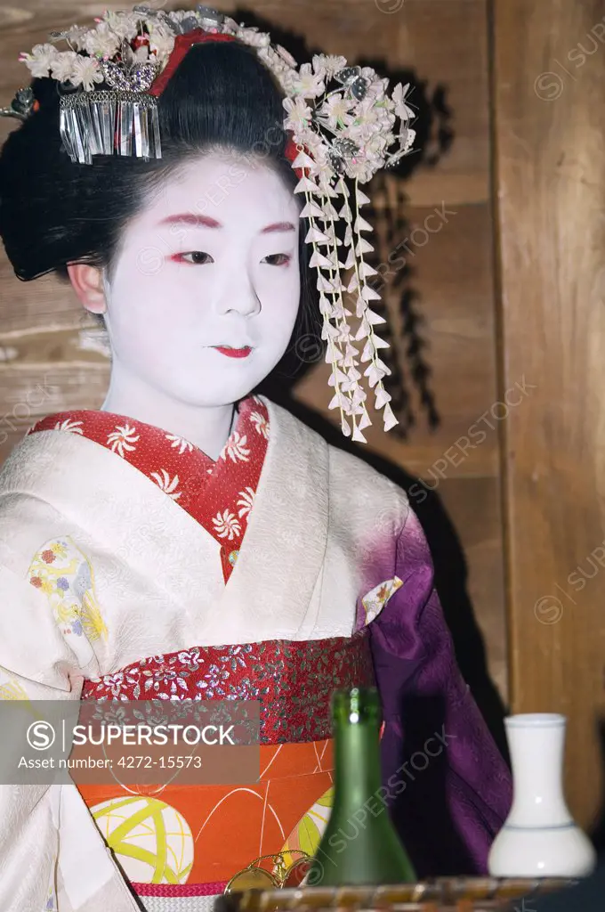 Maiko trainee geisha entertaining at dinner and serving drinks