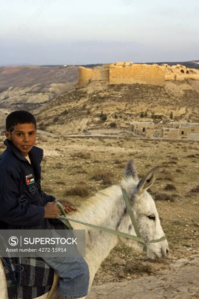 Jordan, Petra Region, Shobak. Boy on a donkey in front of Shobak Castle, which was built in 1115 to guard the road from Egypt to Damascus.