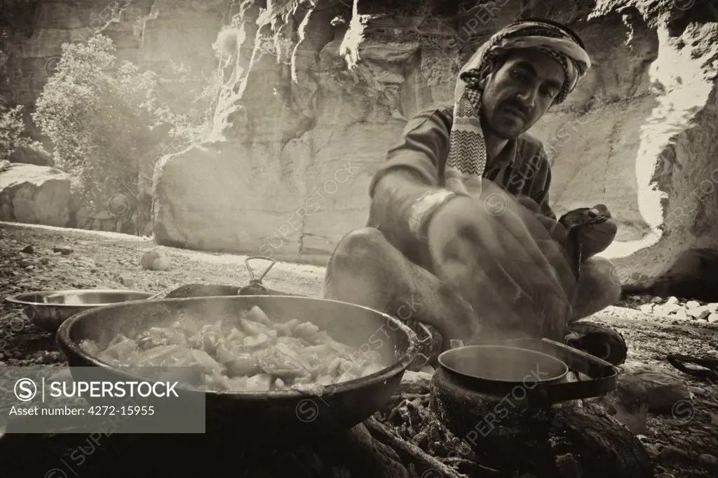 Jordan, Petra Region. Stopping for lunch in the Wadi Daphna, over an open fire a local Bedu guide prepares traditional Jordanian tea and cooks up fresh vegetables (MR)