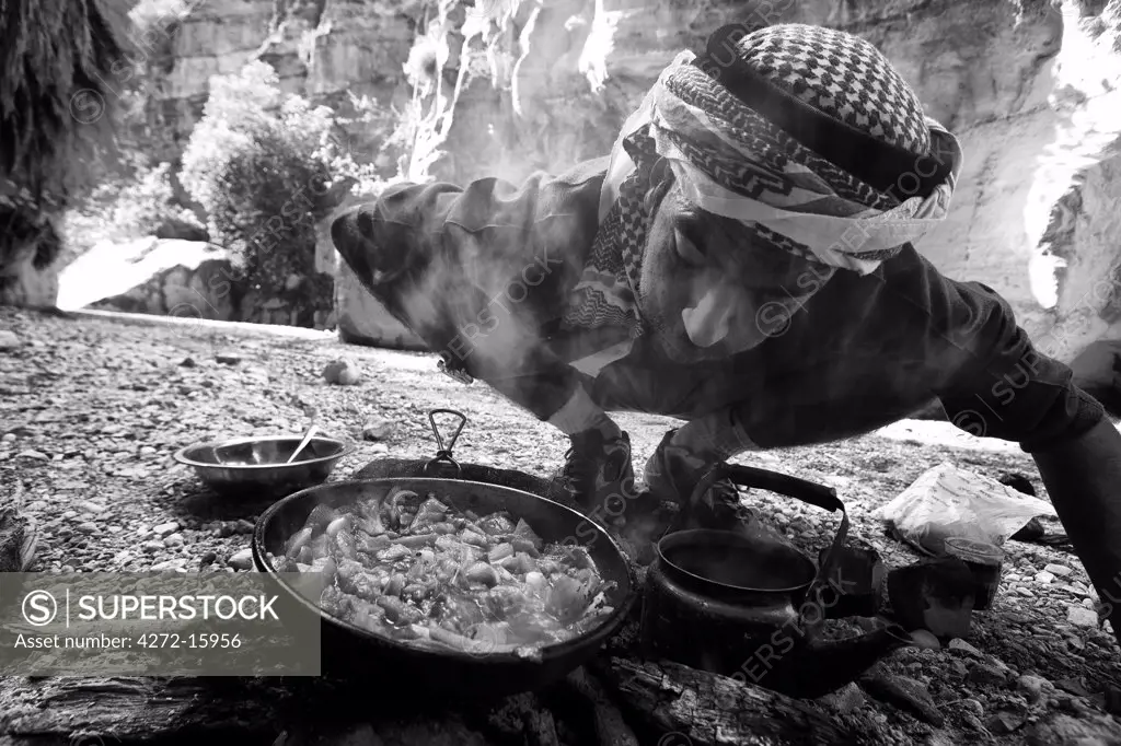 Jordan, Petra Region. Stopping for lunch in the Wadi Daphna, over an open fire a local Bedu guide prepares traditional Jordanian tea and cooks up fresh vegetables (MR)