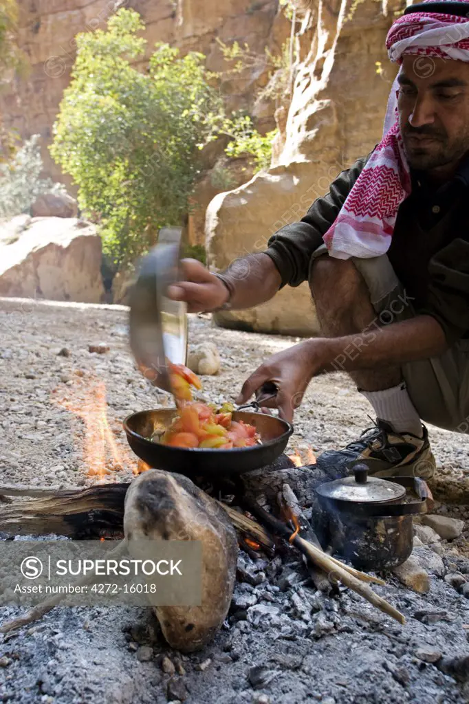 Jordan, Petra, Wadi Daphna. A local beduin guide dressed in traditional clothing prepares a lunch time meal over an open fire in the dead chasm within Wadi Daphna. (MR)