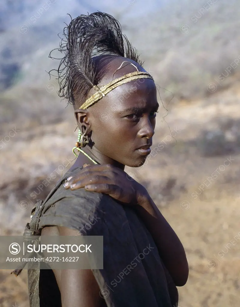 A Samburu boy in reflective mood after his circumcision. A day after the ordeal, he will hang in his pierced earlobes copper earrings normally worn by married women and put on a new headdress of ostrich feathers fastened to a narrow band of plaited fibre, which fits tightly round his forehead.