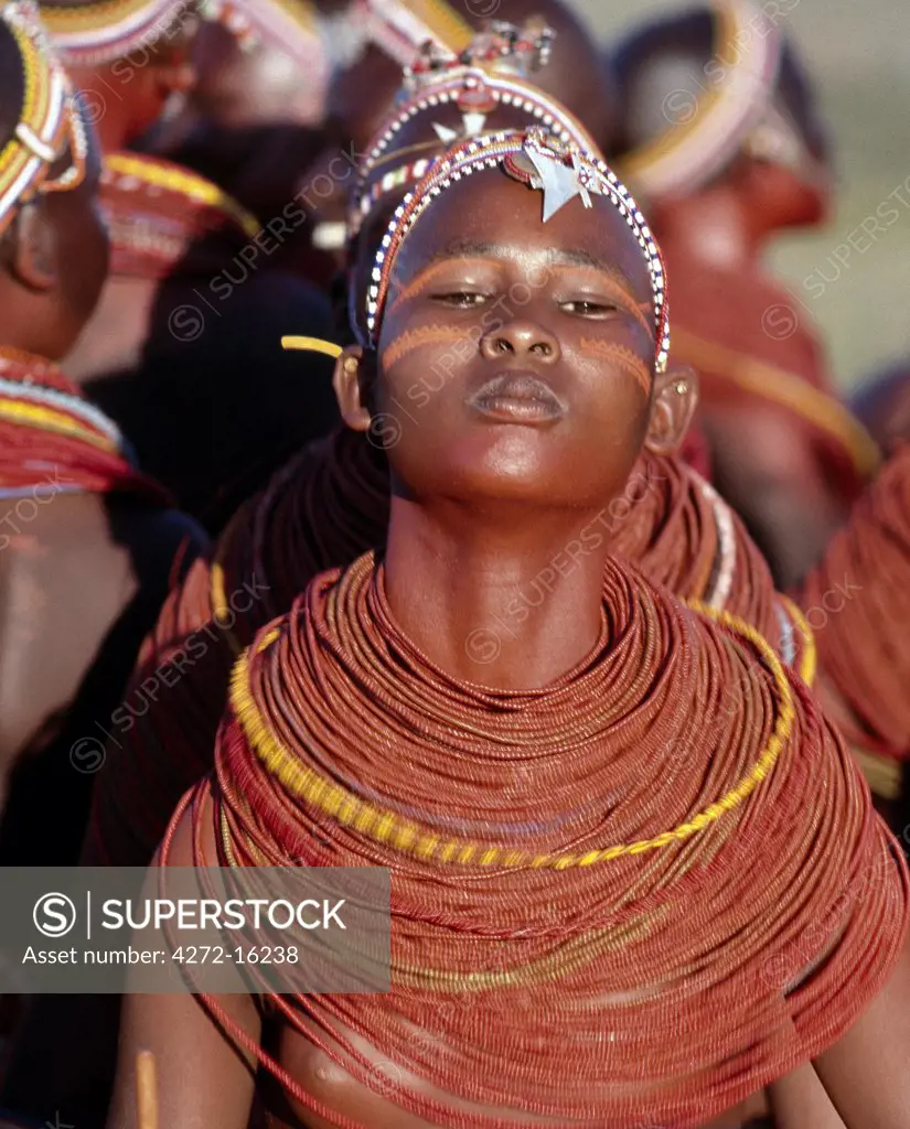 A young Samburu girl dances during a wedding celebration. By arching her back and thrusting out her chest, she flicks her beaded necklaces up and down while dancing silently to the songs of the warriors. Her body and necklace have been smeared with red ochre.