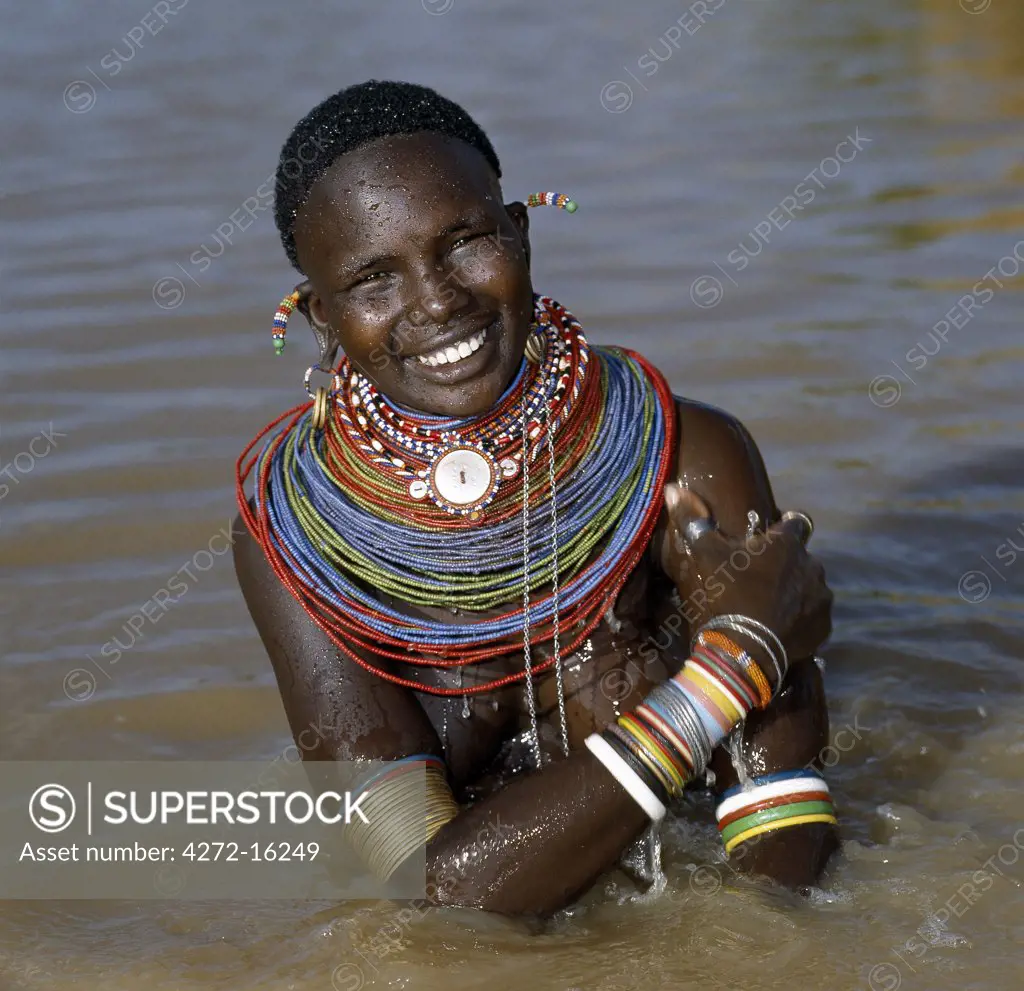 A Samburu woman resplendent in her beaded necklaces and numerous bracelets makes best use of a large rainwater pond to wash herself. Water is scarce in much of Samburuland.
