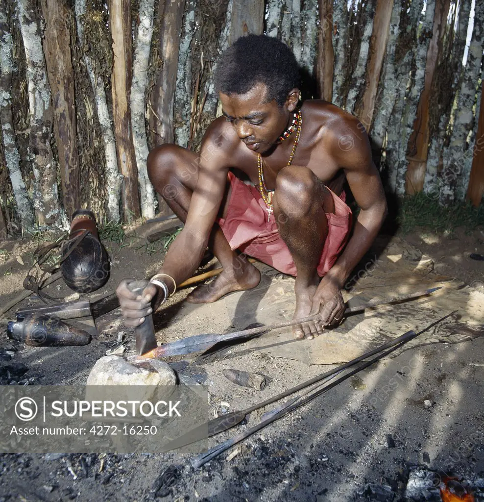 A Samburu blacksmith fashions a spear from an iron rod. Blacksmiths have their own special clan within the tribe and are not allowed to marry girls from other clans.  Their skills are handed down from father to son. This man will take two days to make a spear for which he will be paid a goat.